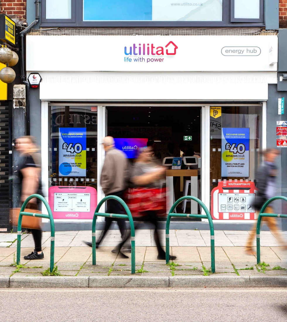 Shop front of Utilita Energy Hub on the high street with members
                   of the public walking past
