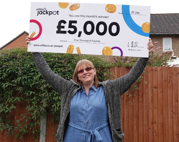 Woman holding a large check saying £5000